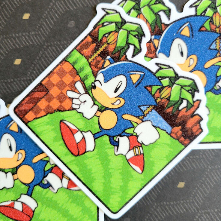 Glitter Sonic Sticker photograph of a square shaped sticker depicting the green hill zone with sonic running through it. the sticker is texture sand glitter