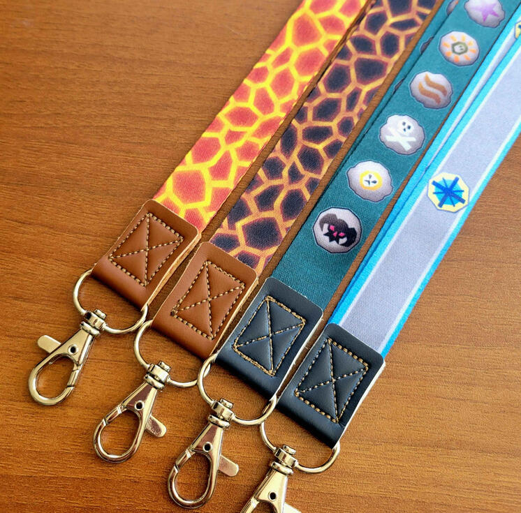 photograph of four lanyards inspired by old school runes scape. the lanyards include a fire cape, infernal cape, teal lanyard with runes, and quest cape