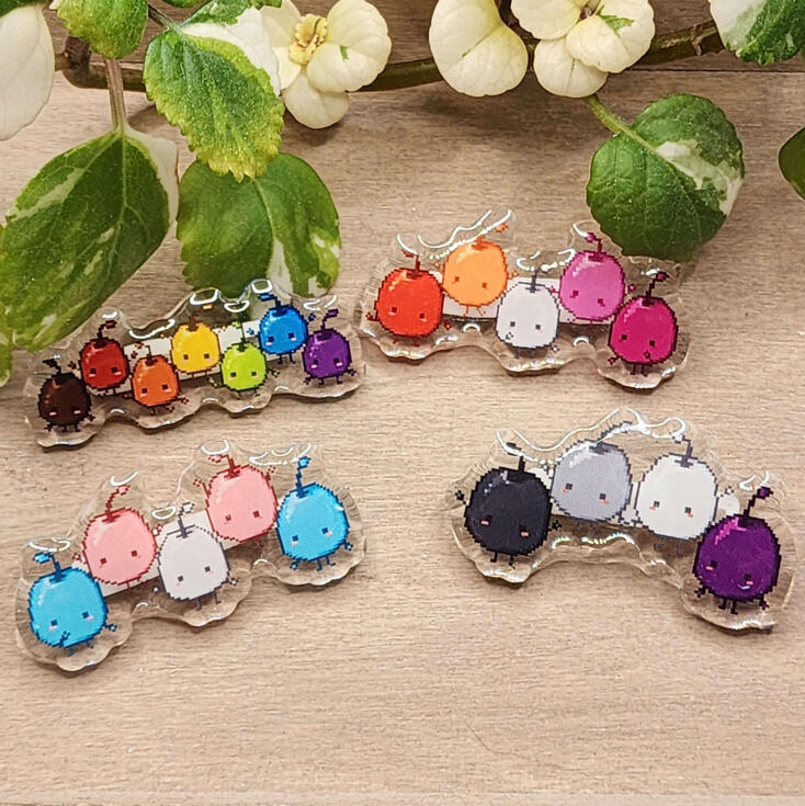 Junimos photograph of acrylic pins. the pins depict junimos in pride colors